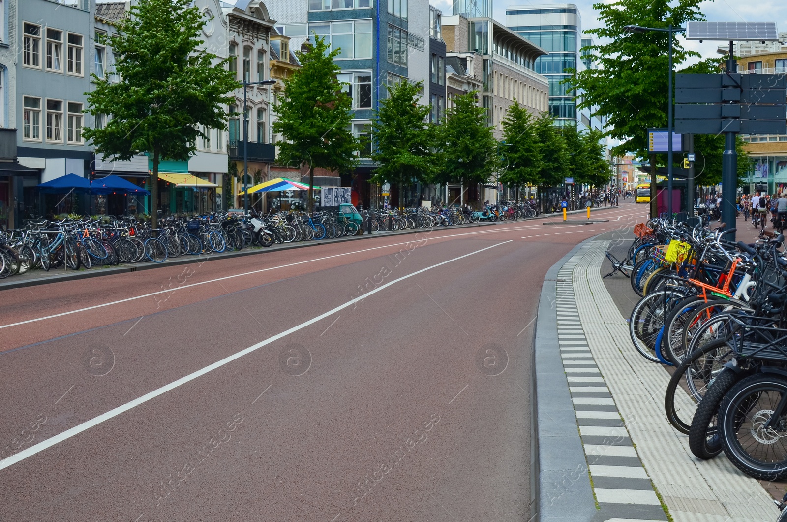 Photo of Empty asphalt road and parked bicycles on pavement at city