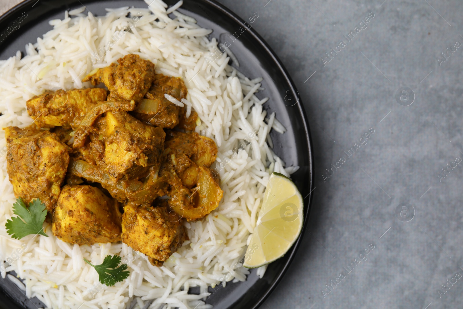 Photo of Delicious chicken curry with rice on grey table, top view