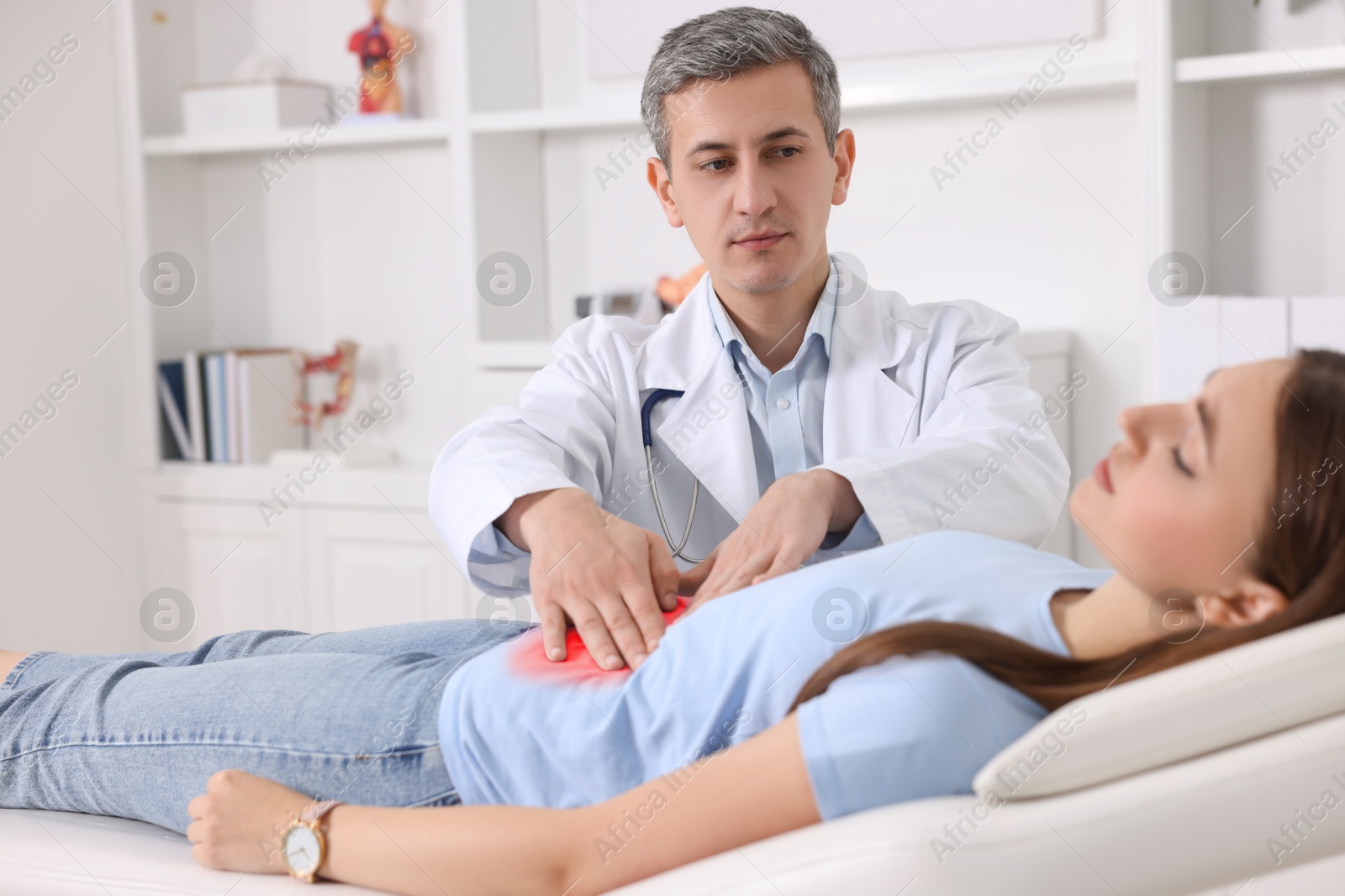 Image of Gastroenterologist examining patient with stomach pain on couch in clinic