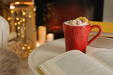 Photo of Cup of cocoa, book and cookie on white table indoors