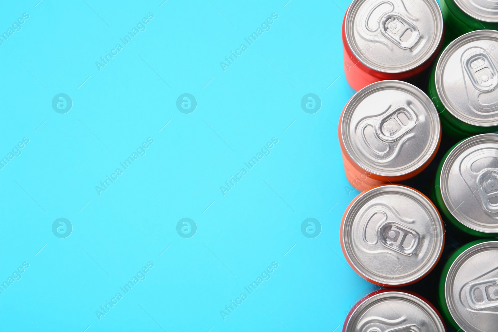 Photo of Energy drink in cans on light blue background, top view. Space for text