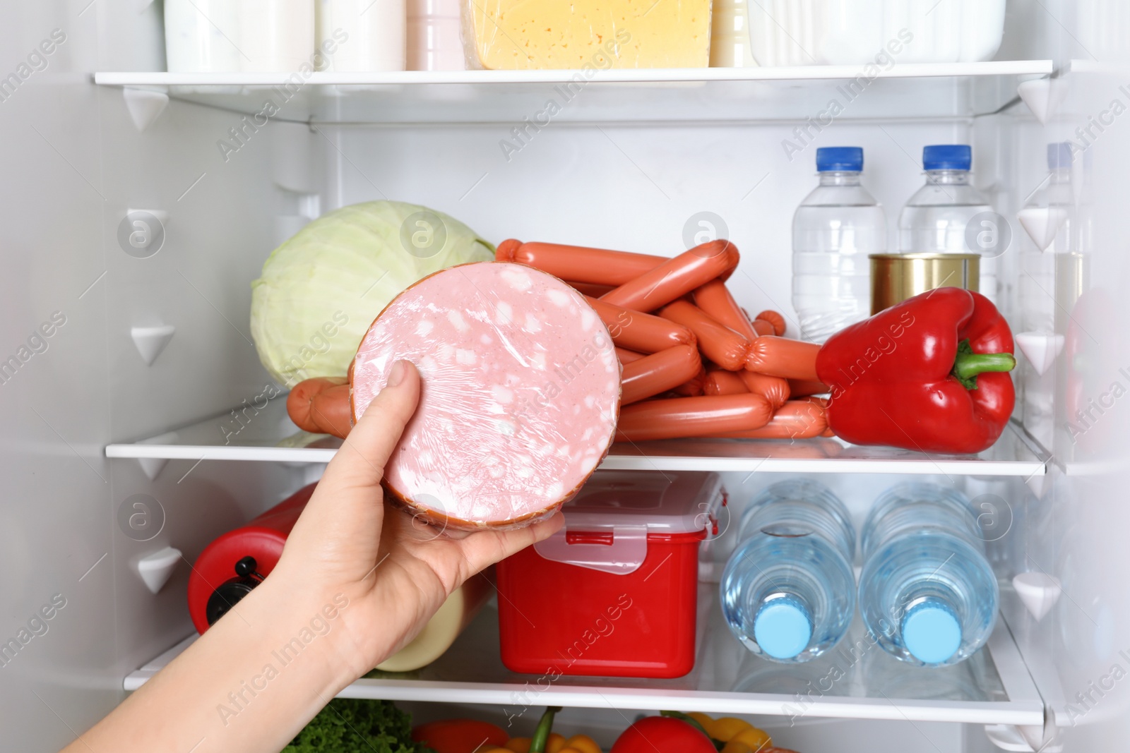 Photo of Woman taking tasty sausage from refrigerator, closeup