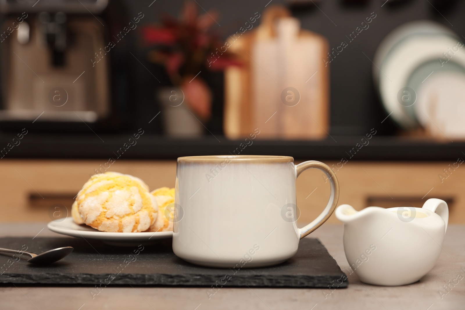 Photo of Cup of coffee, milk and cookies on table in kitchen