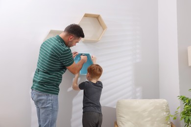 Father and son installing shelves on wall at home. Repair work