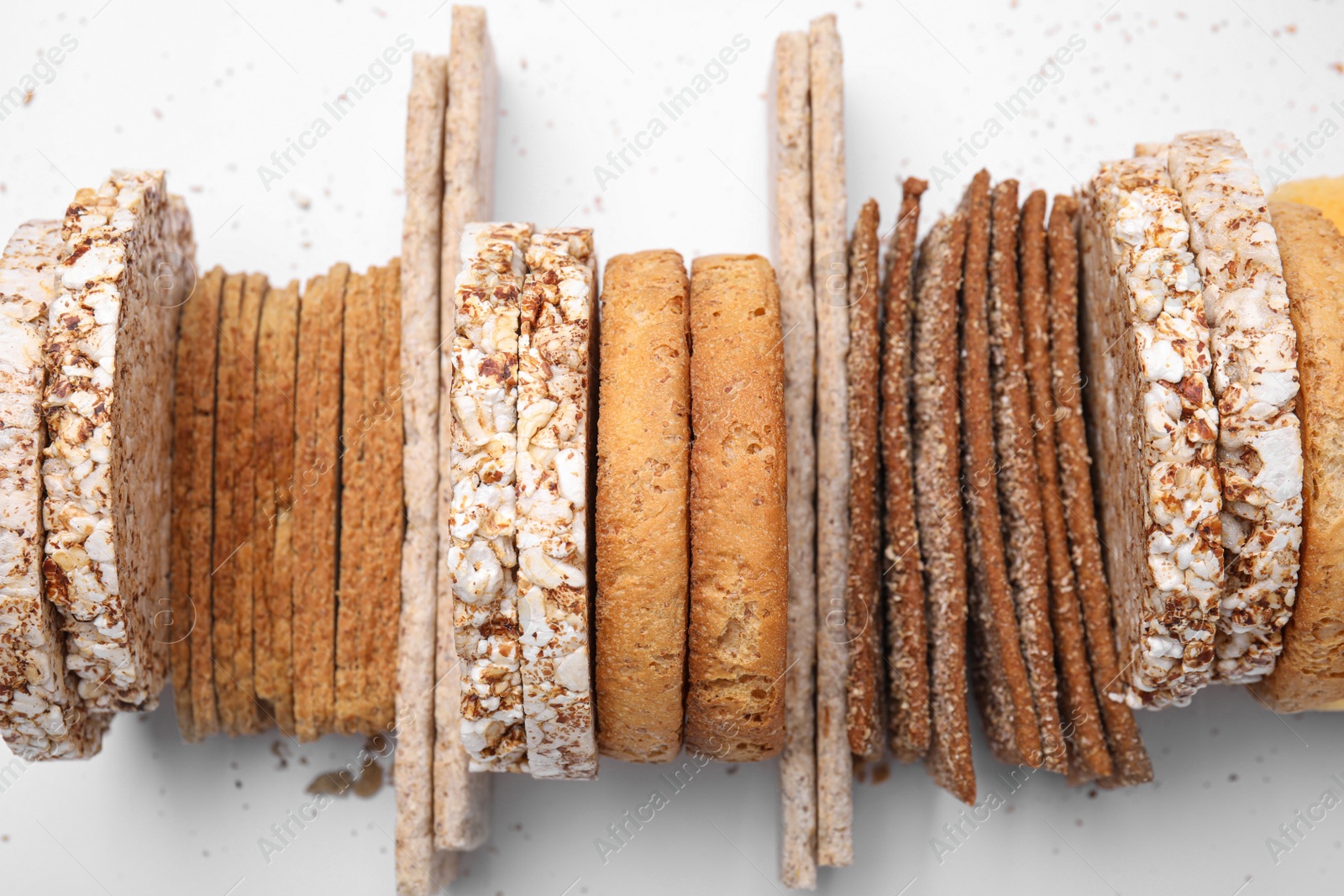 Photo of Many fresh rye crispbreads, crunchy rice cakes and rusks on white background, top view