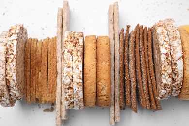 Photo of Many fresh rye crispbreads, crunchy rice cakes and rusks on white background, top view