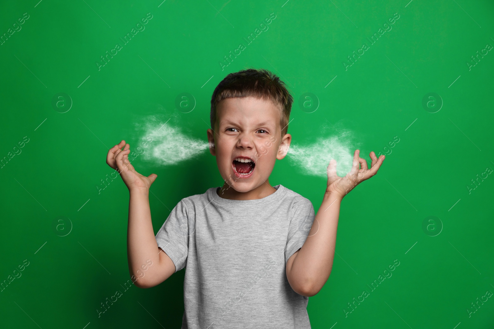 Image of Aggressive little boy with steam coming out of his ears on green background
