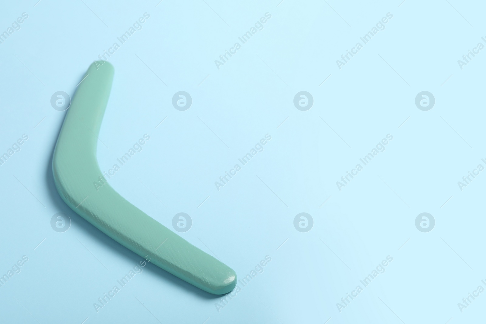 Photo of Wooden boomerang on light blue background. Space for text