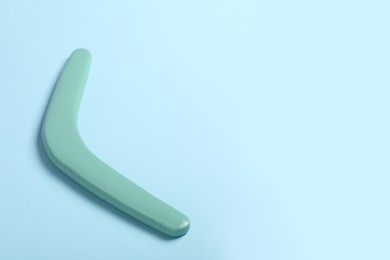 Photo of Wooden boomerang on light blue background. Space for text