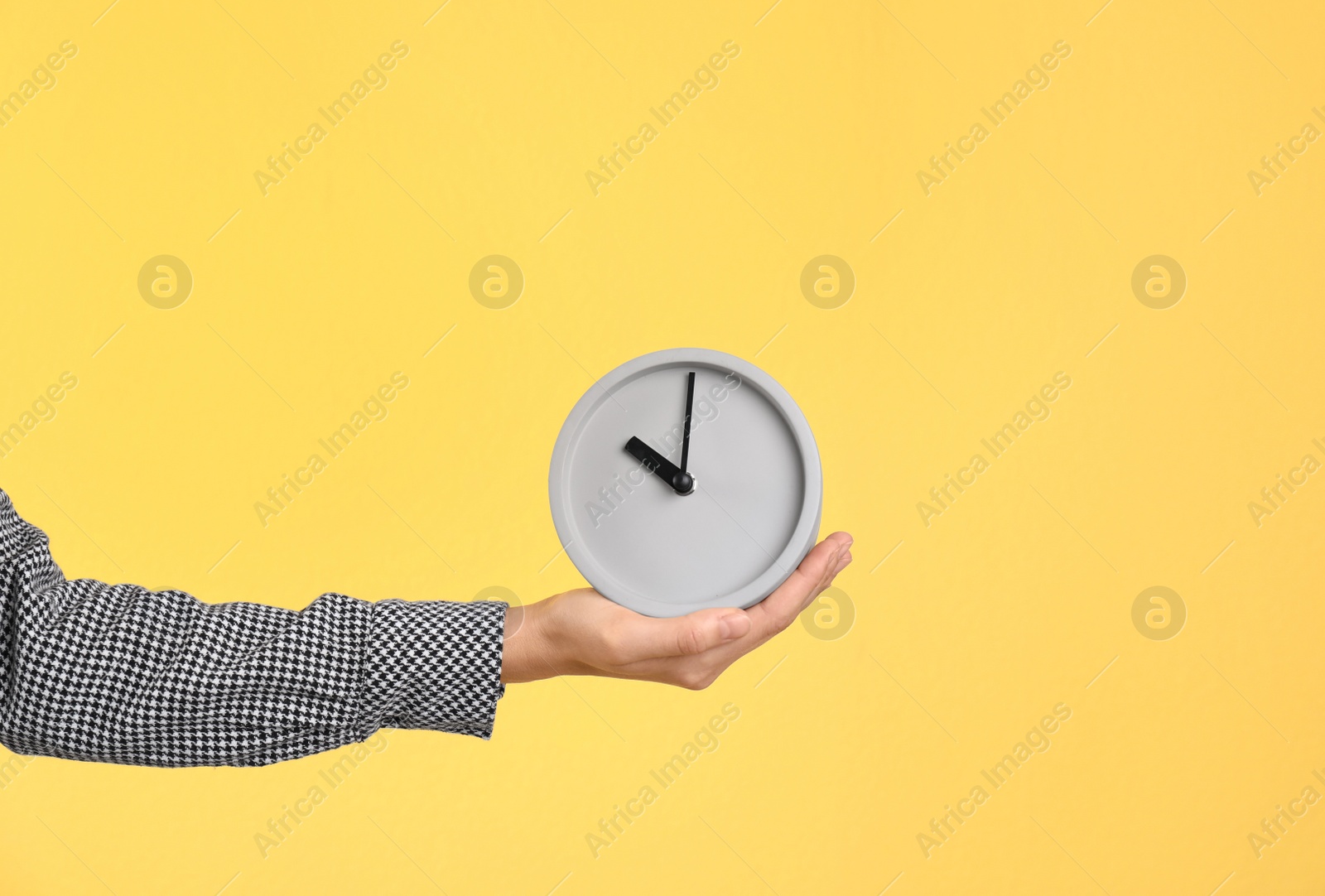 Photo of Young woman holding clock on color background. Time management