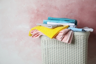 Basket with clean laundry on pink background, space for text