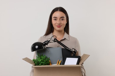 Photo of Unemployed woman with box of personal office belongings on white background