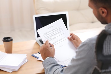 Photo of Man working with documents at wooden table in office, back view