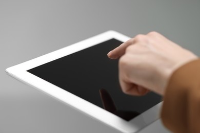 Closeup view of woman using modern tablet on light grey background