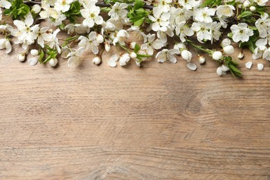 Photo of Blossoming spring tree branches as border on wooden background, flat lay. Space for text