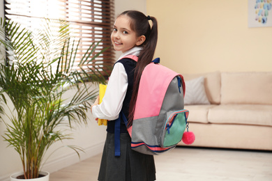 Little girl in uniform with school stationery at home
