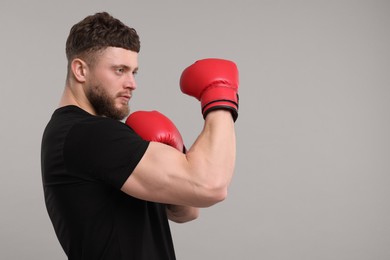 Photo of Man in boxing gloves on grey background. Space for text