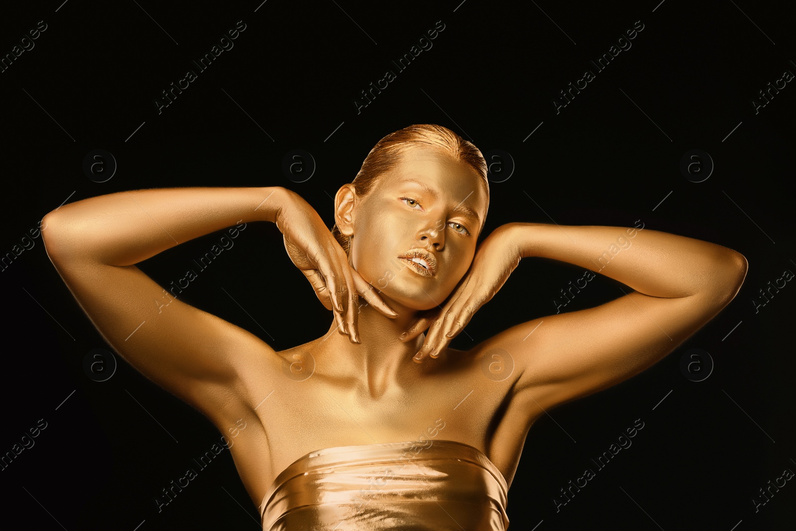 Photo of Portrait of beautiful lady with gold paint on skin against black background