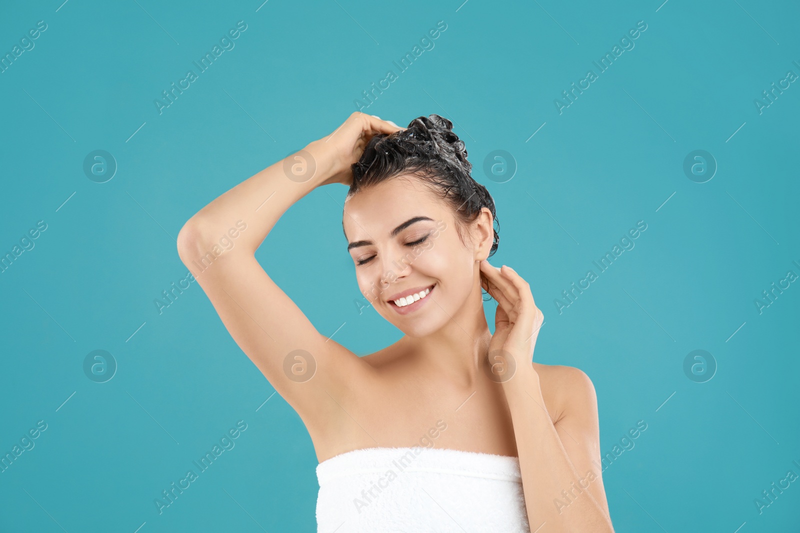 Photo of Beautiful young woman washing hair on light blue background