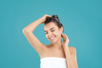 Photo of Beautiful young woman washing hair on light blue background