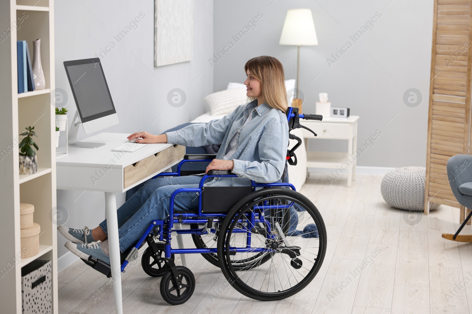 Photo of Woman in wheelchair using computer at table in home office