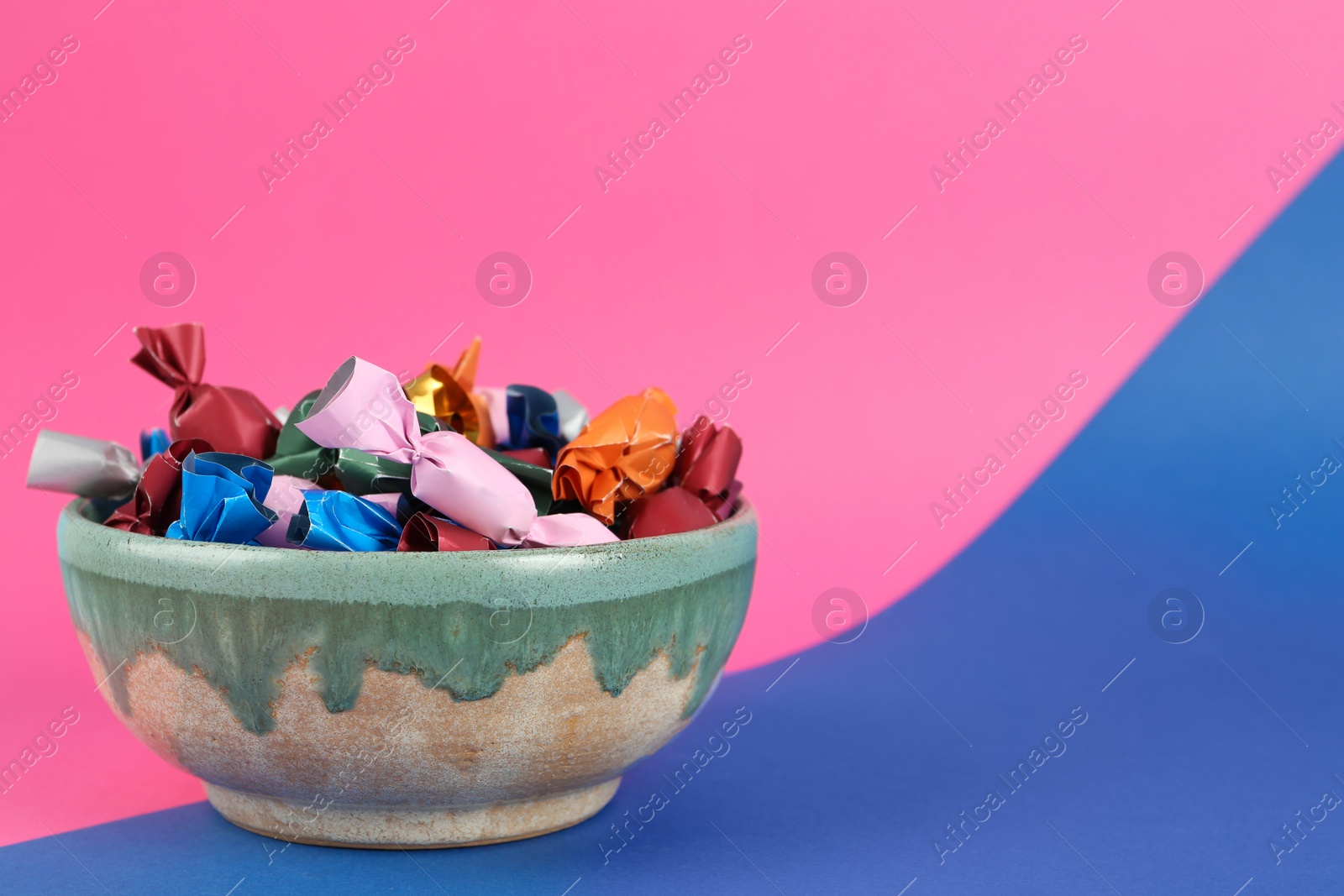 Photo of Candies in different wrappers on color background, space for text