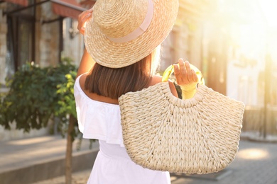 Photo of Young woman with stylish straw bag outdoors