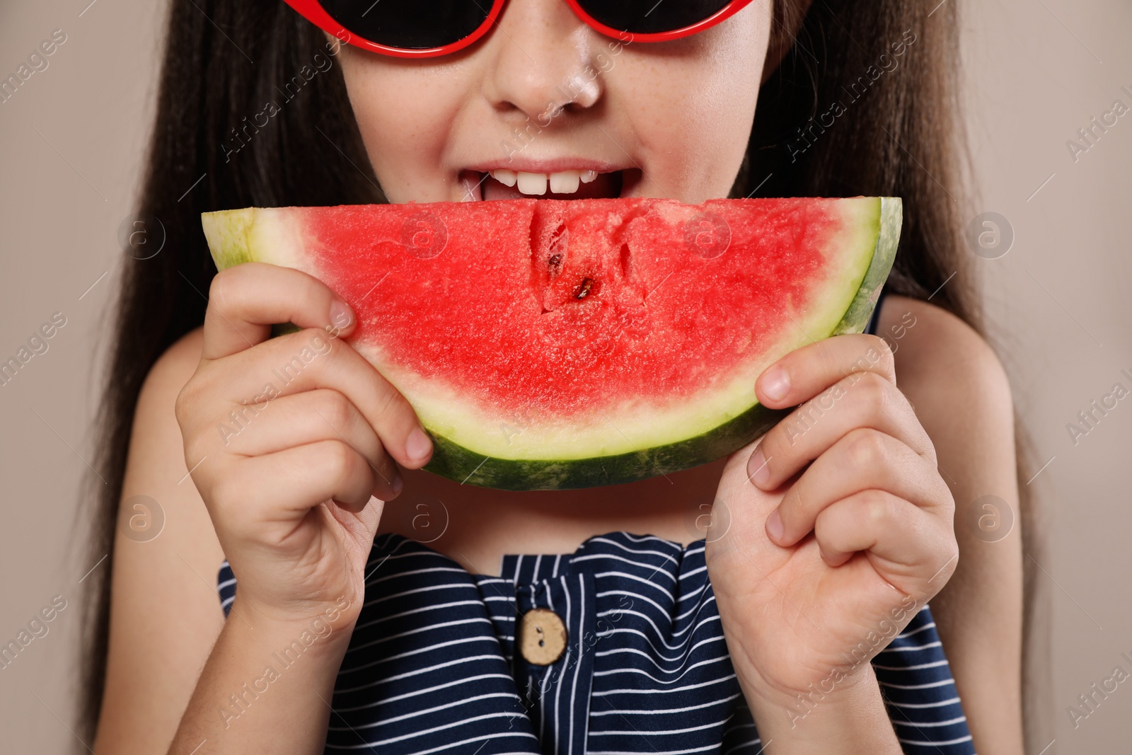 Photo of Cute little girl with watermelon on beige background, closeup