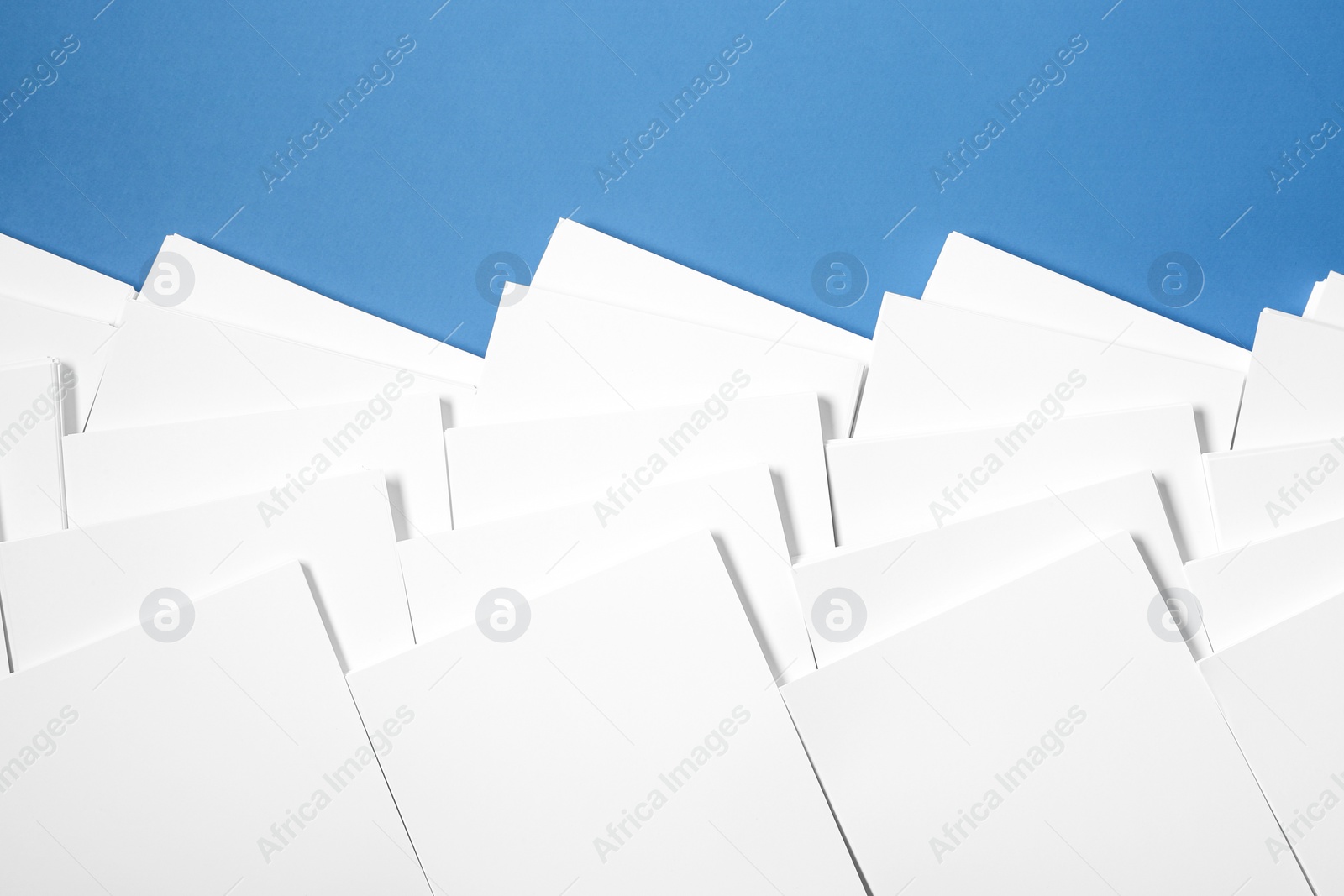 Photo of Many stacks of paper sheets on blue background, flat lay