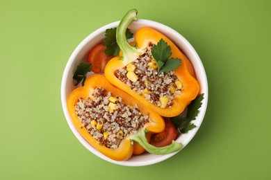 Photo of Quinoa stuffed bell pepper and parsley in bowl on green background, top view