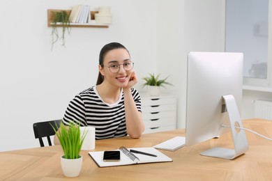 Photo of Home workplace. Portrait of happy woman at wooden desk in room