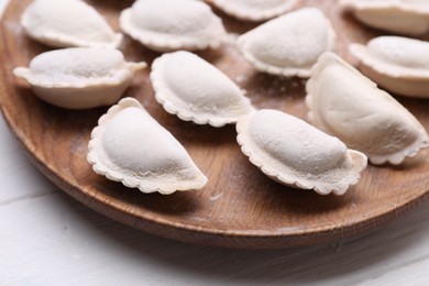 Photo of Raw dumplings (varenyky) on wooden plate, closeup