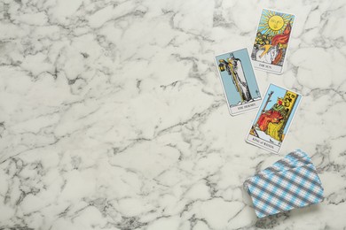 Photo of Tarot cards on white marble table, flat lay. Space for text