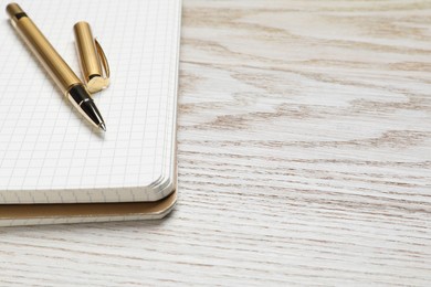 Photo of Ballpoint pen and notebook on wooden table, space for text