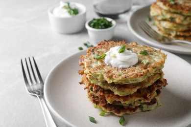 Photo of Delicious zucchini fritters served on light table, closeup
