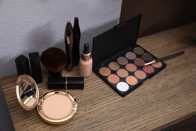 Photo of Different decorative cosmetic products on wooden table, above view