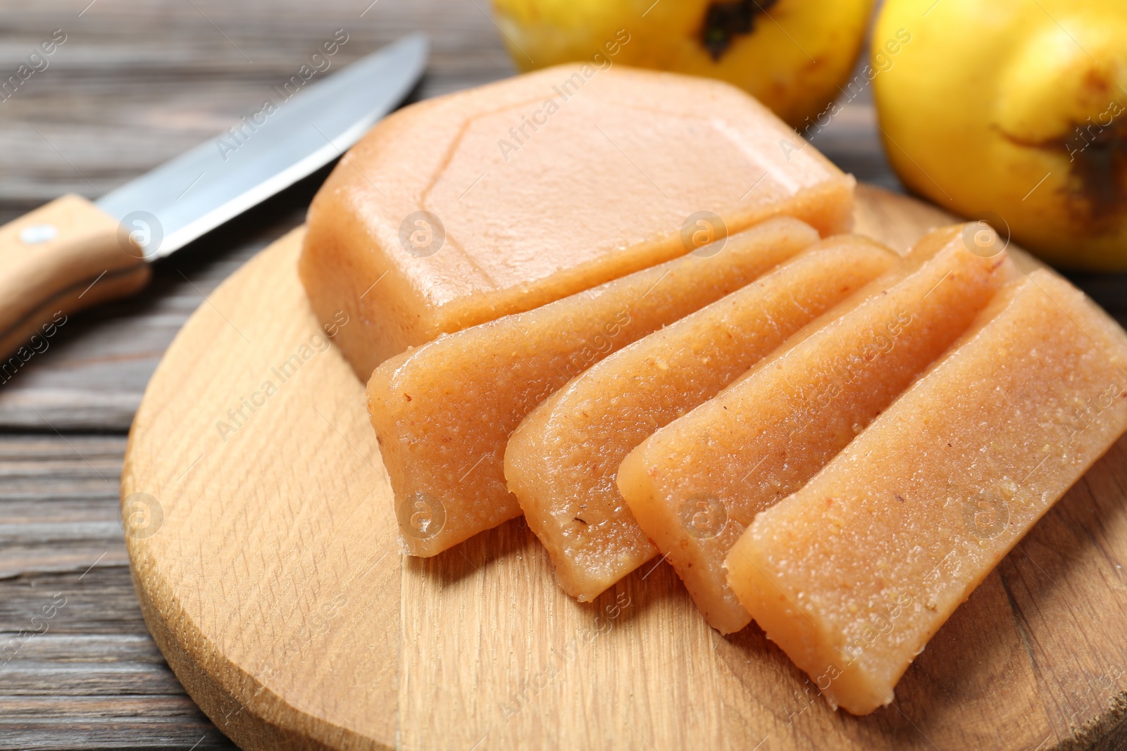 Photo of Tasty sweet quince paste, fresh fruits and knife on wooden table, closeup