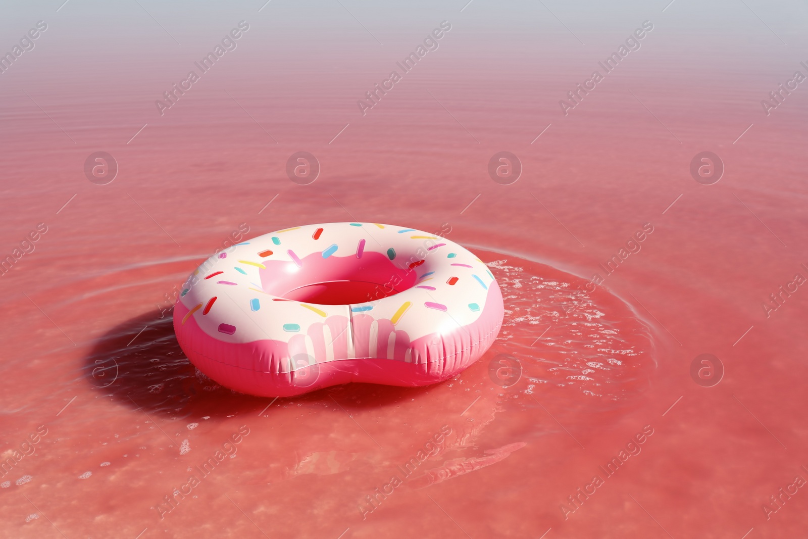 Photo of Inflatable ring floating in pink lake on sunny day