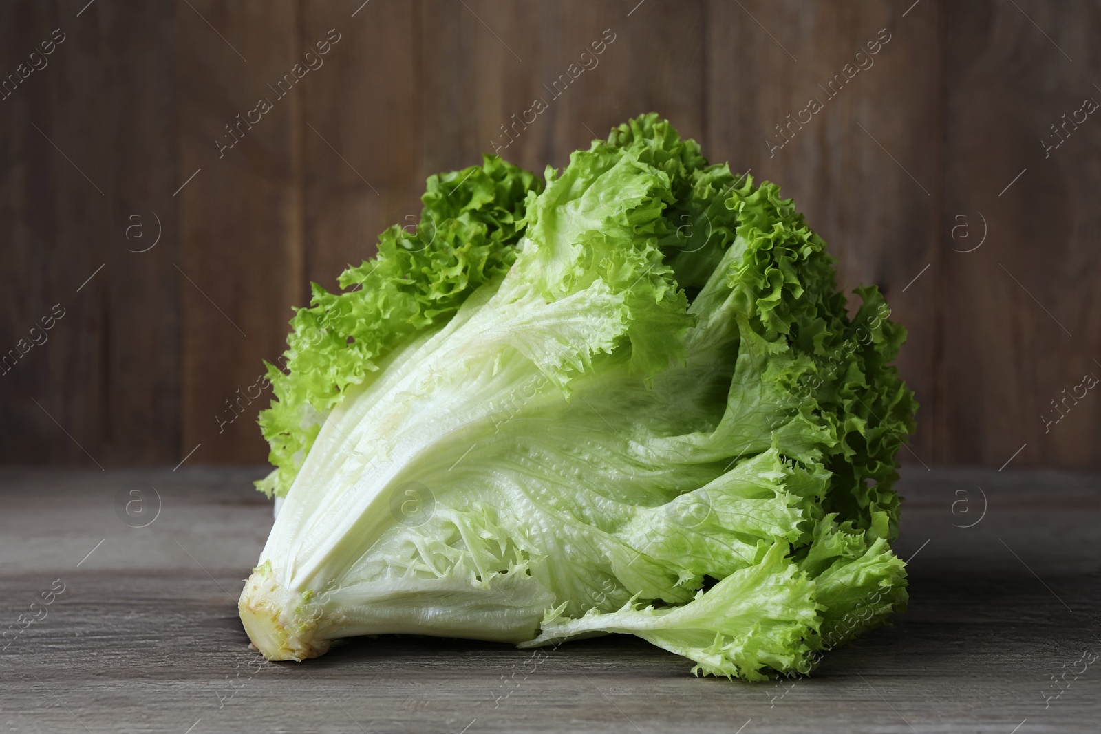 Photo of Fresh lettuce on wooden table. Salad greens