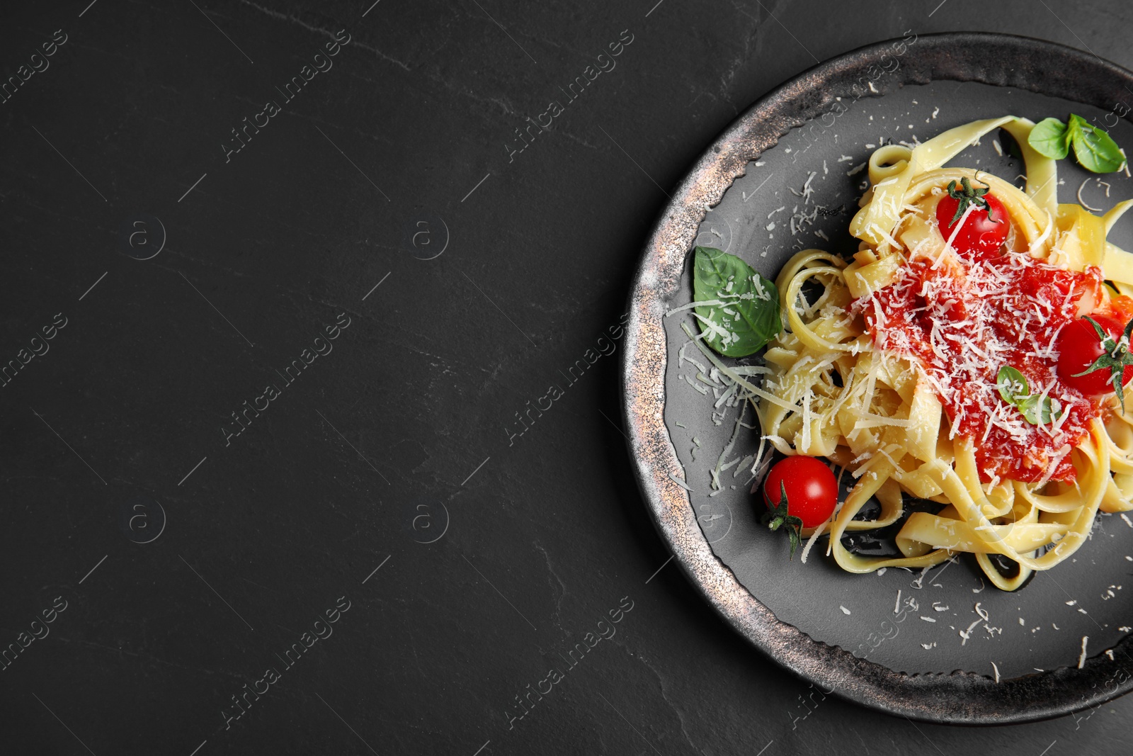 Photo of Tasty pasta on black table, top view. Space for text