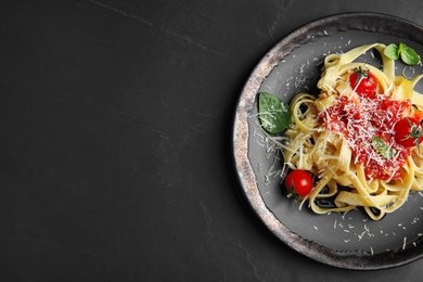 Photo of Tasty pasta on black table, top view. Space for text