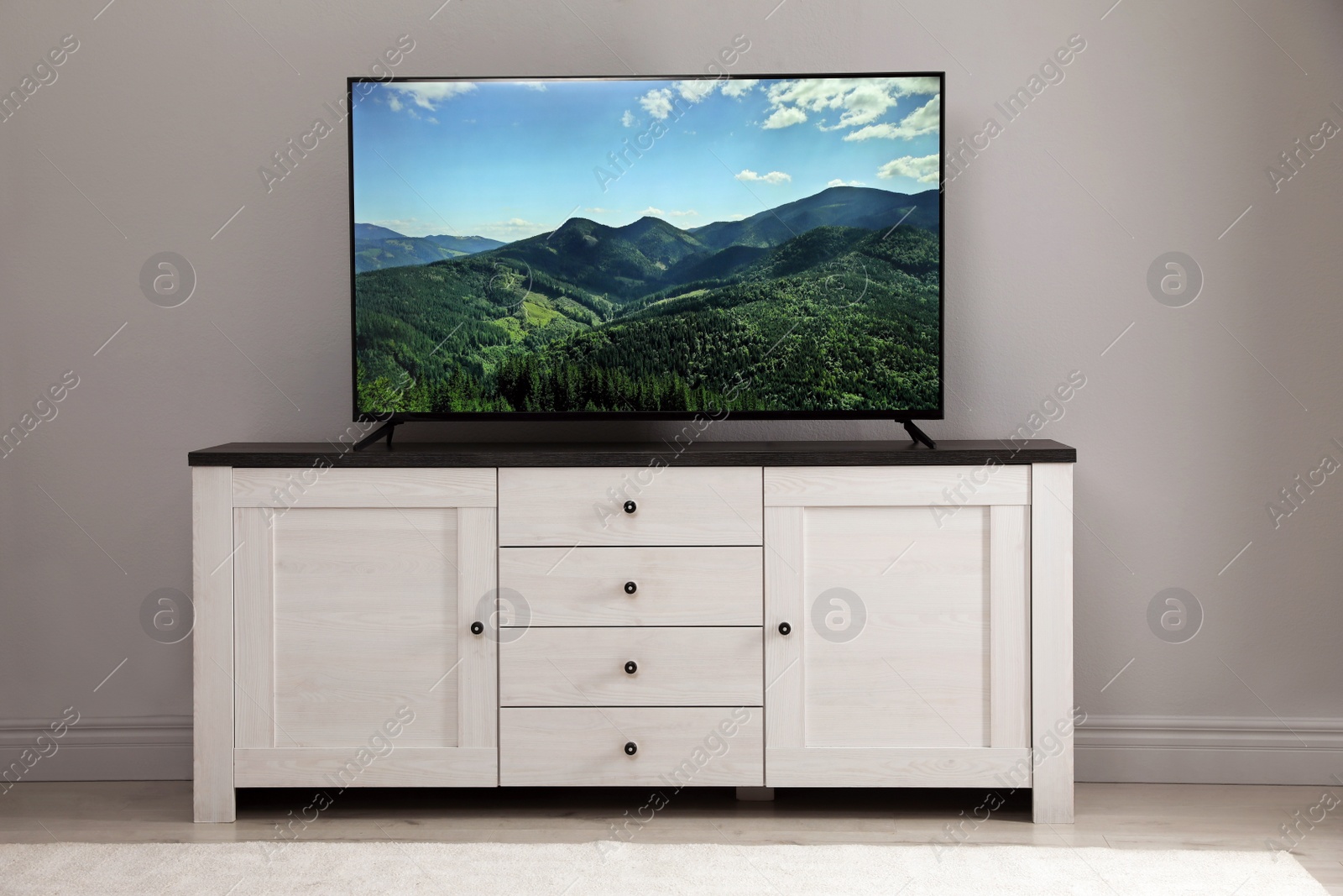 Photo of Modern TV on cabinet near white wall in room