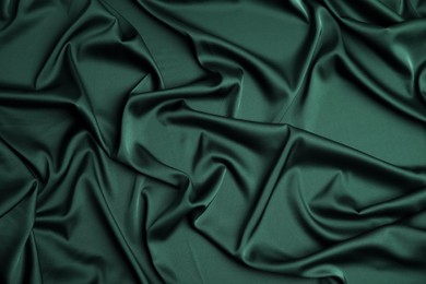 Crumpled dark green silk fabric as background, top view
