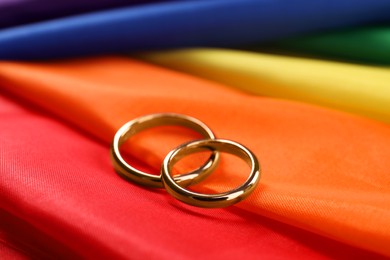 Wedding rings on rainbow LGBT flag, closeup