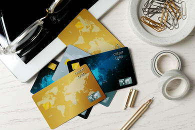 Photo of Different credit cards, tablet and stationery on white wooden table, flat lay