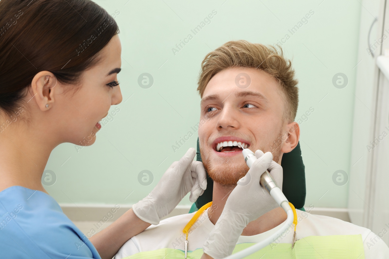 Photo of Professional dentist working with patient in modern clinic. Teeth care