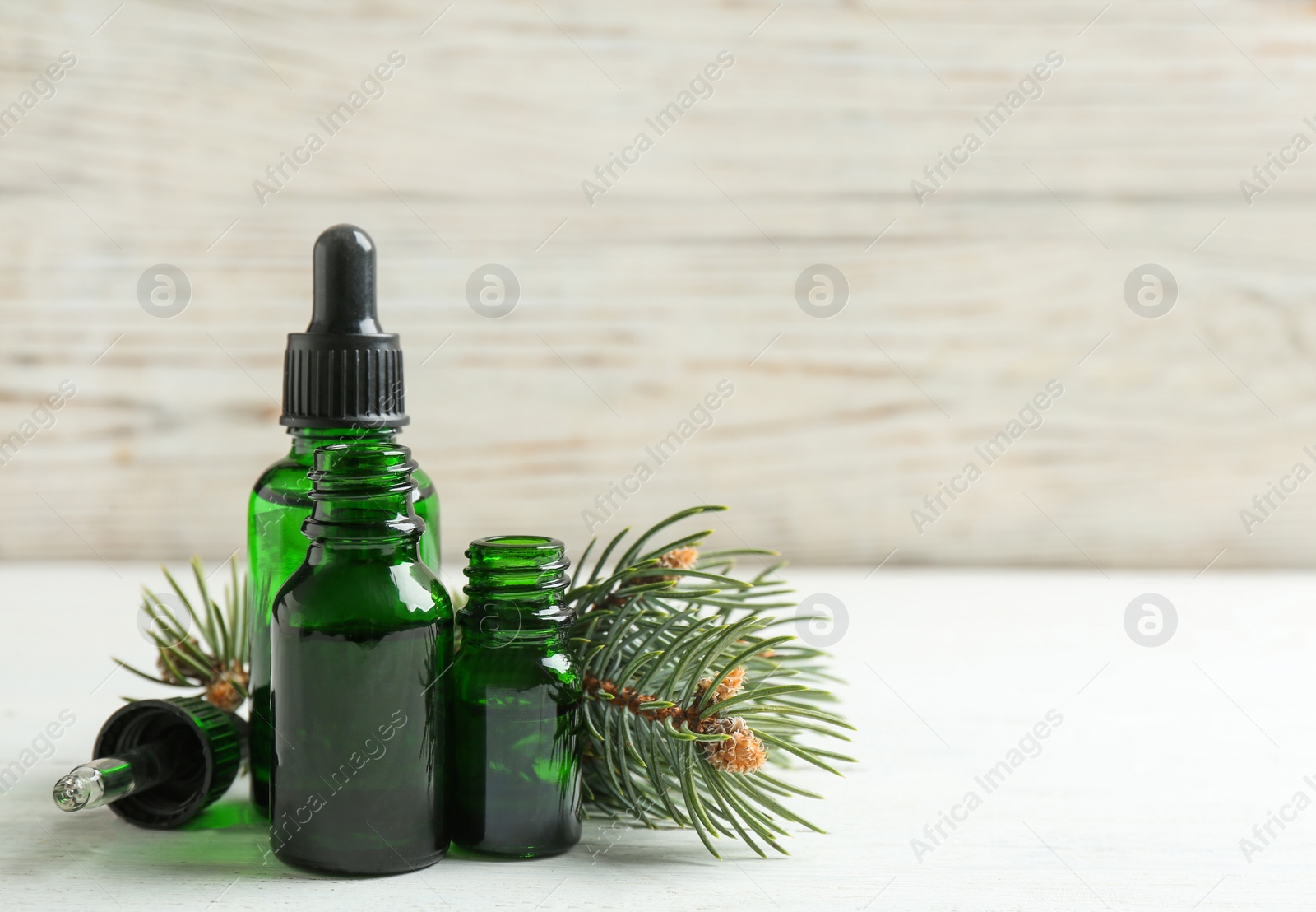 Photo of Composition with bottles of conifer essential oil on white wooden table. Space for text