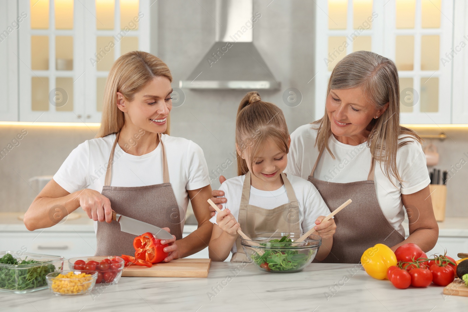 Photo of Three generations. Happy grandmother, her daughter and granddaughter cooking together in kitchen