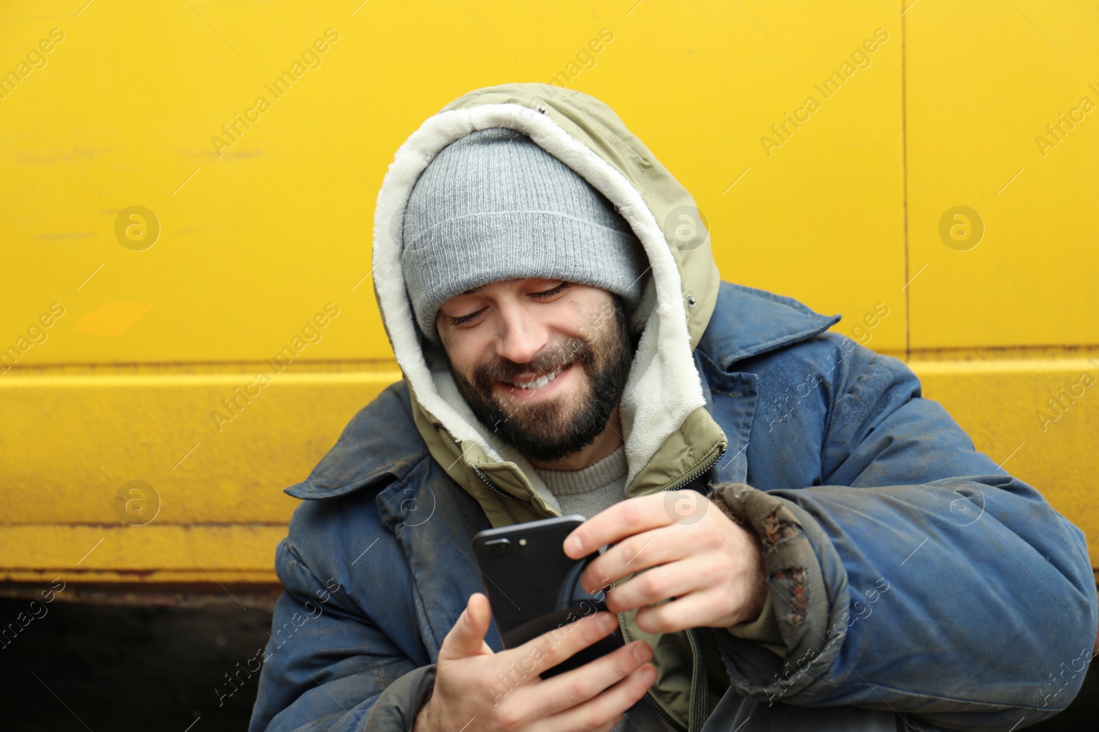 Photo of Poor homeless man with stolen smartphone outdoors
