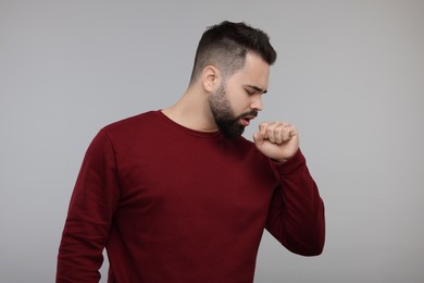 Sick man coughing on gray background. Cold symptoms